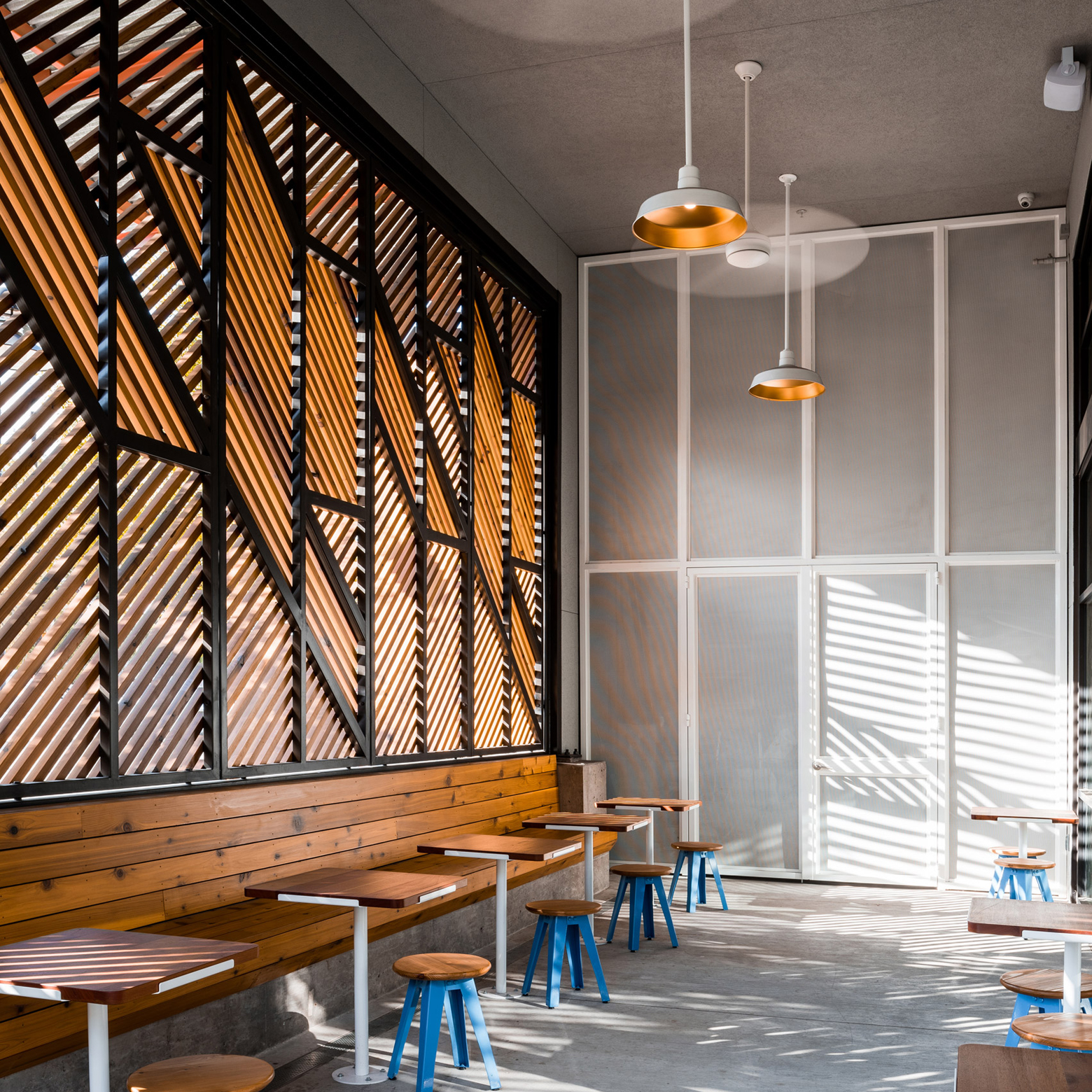 幾何学的な目隠しで店舗内の光をコントロールしたコーヒーショップの木製ブラインド